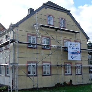 Gerüst an alter Fassade eines Wohnhauses - mit weißem Werbeplakat des Malerbetriebs Benzrath